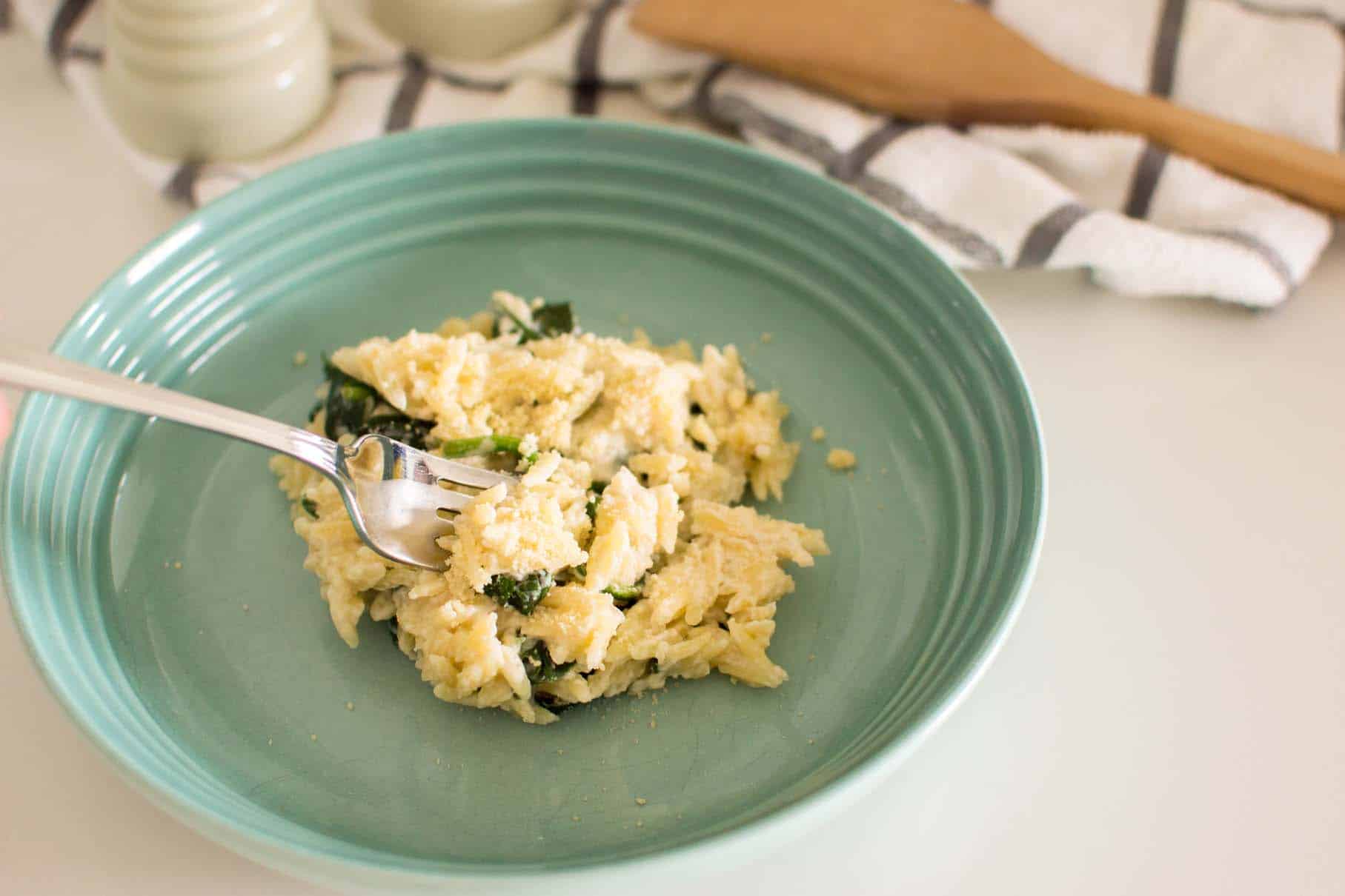 Creamy spinach parmesan orzo garnished with extra parmesan cheese