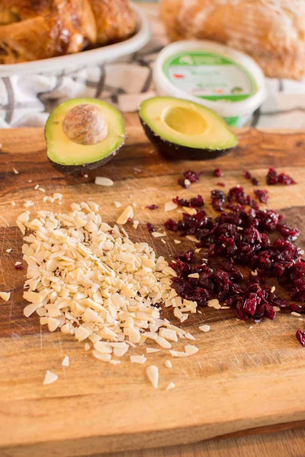 Shredded chicken, avocado, craisins, and almonds prepared for chicken salad