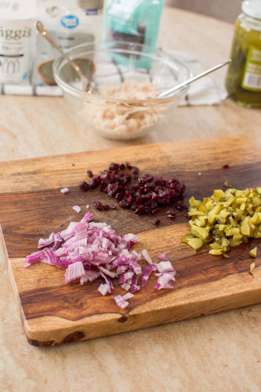 Chopped red onion, dill pickles, and craisins prepared for chicken salad