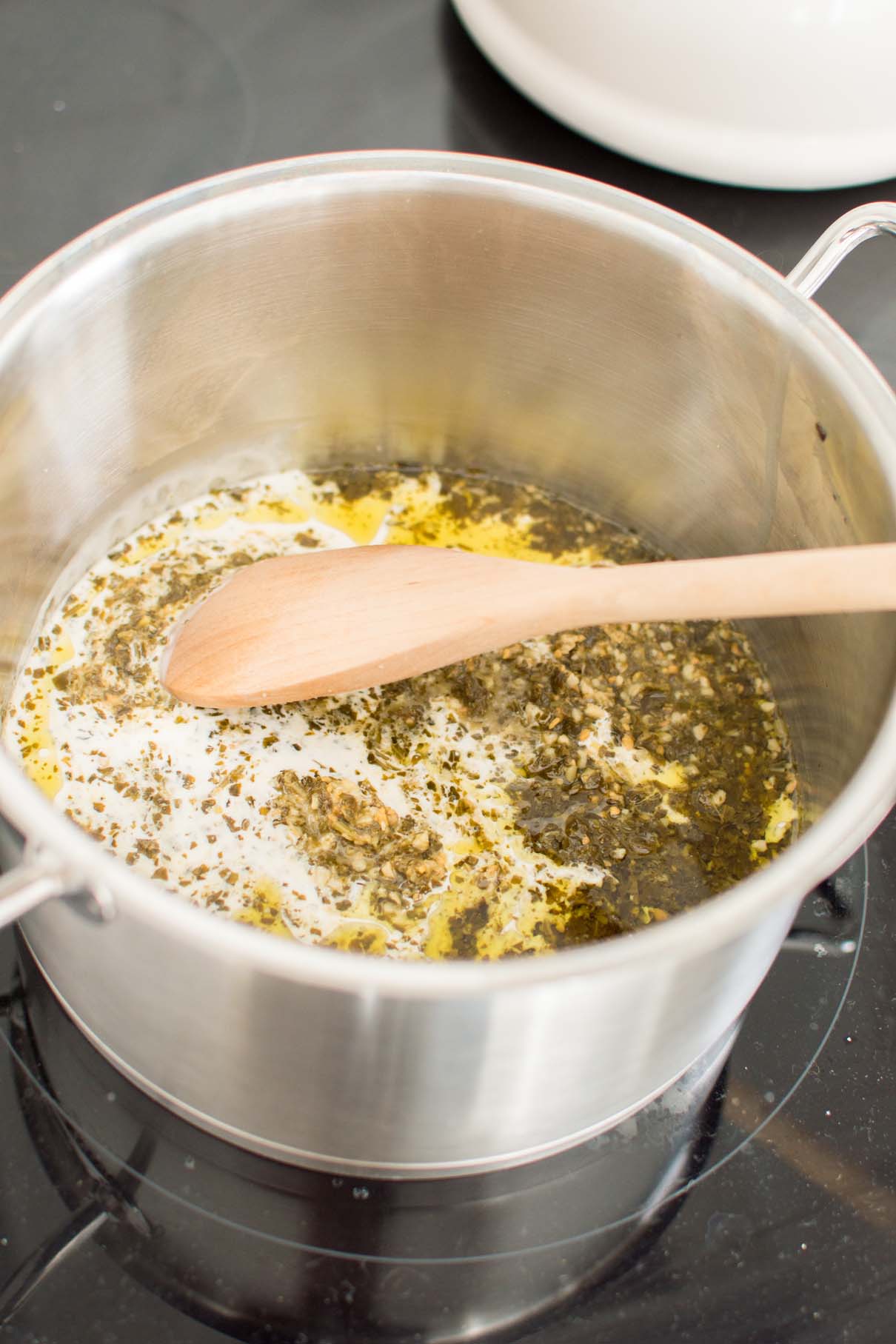 Cream and pesto simmering on a stove in a large pot