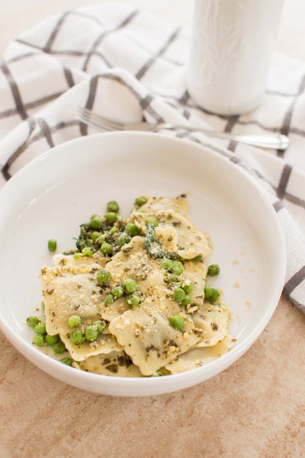 Cheese ravioli coated in creamy basil pesto sauce with peas and spinach